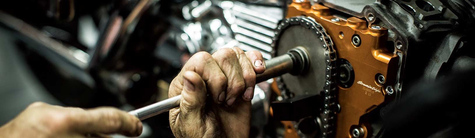 A closeup of a hand turning a tool on an engine.